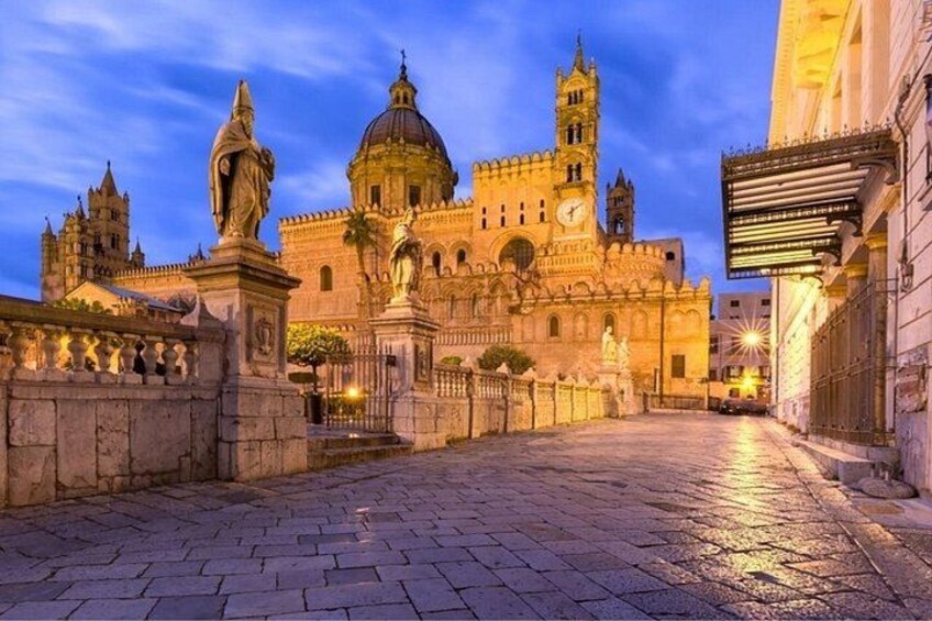 A historic building with a dome and clock tower, a paved street, and a statue. 2