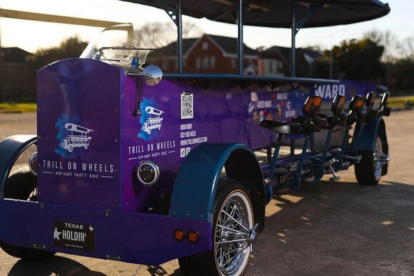 A purple tricycle with 'Trill on Wheels' branding, a Texas license plate, and a QR code. 4
