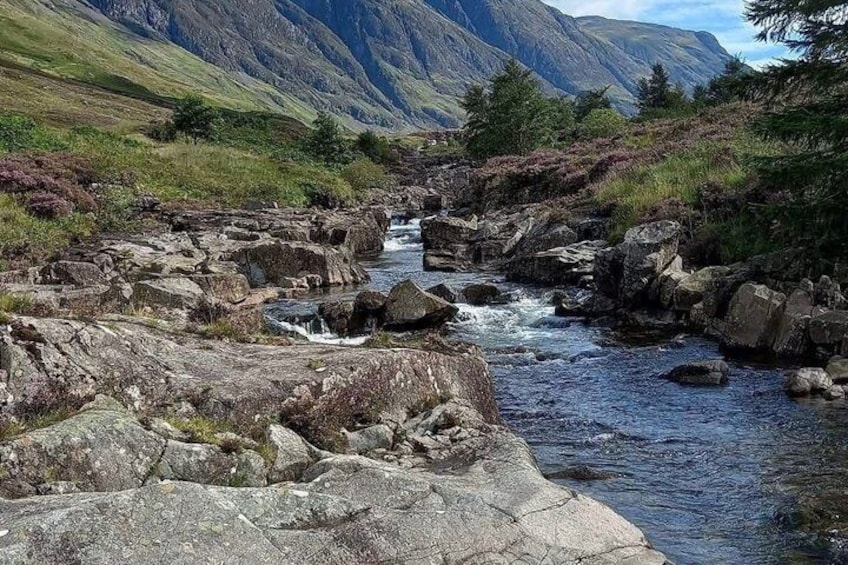 A river flowing through a rocky landscape with mountains in the background. 2