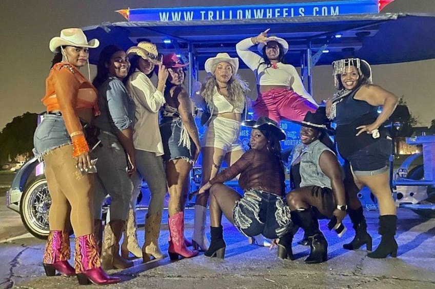 A group of people posing in front of a vehicle with a website address on the roof. 1