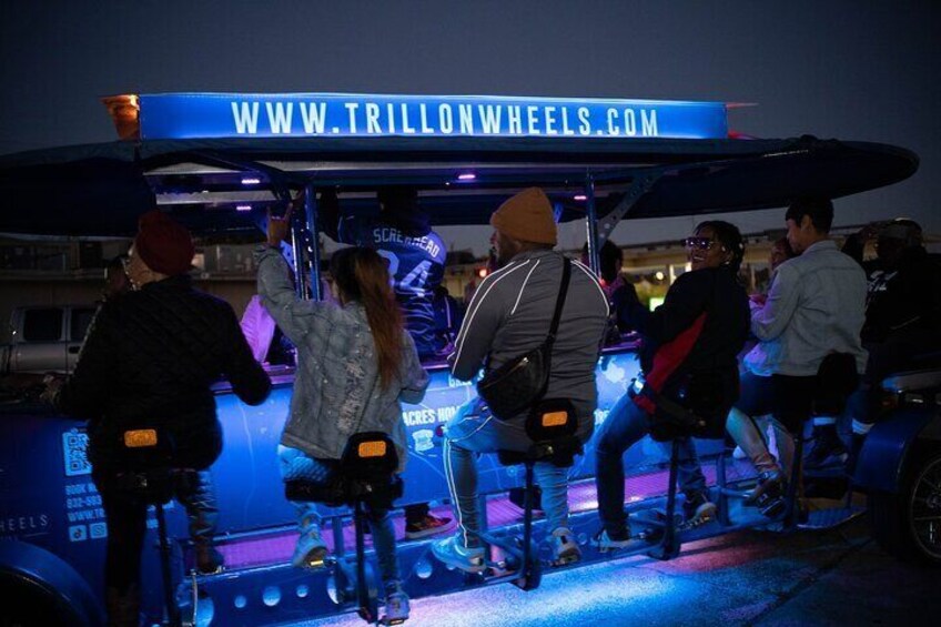 People riding a vehicle with a sign reading "WWW.TRILLONWHEELS.COM". 1