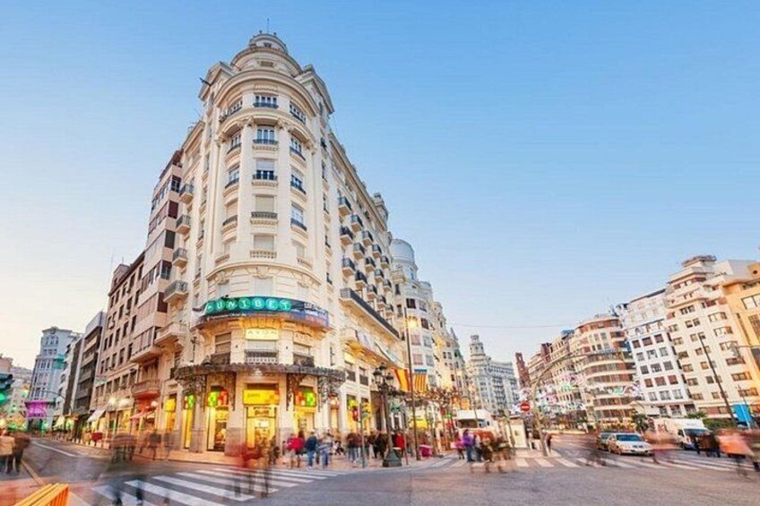 Un edificio de varios pisos con fachada curva, un letrero llamativo y un animado ambiente callejero. 3