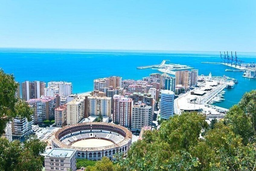 A coastal cityscape with a large stadium, high-rise buildings, and a marina. 2