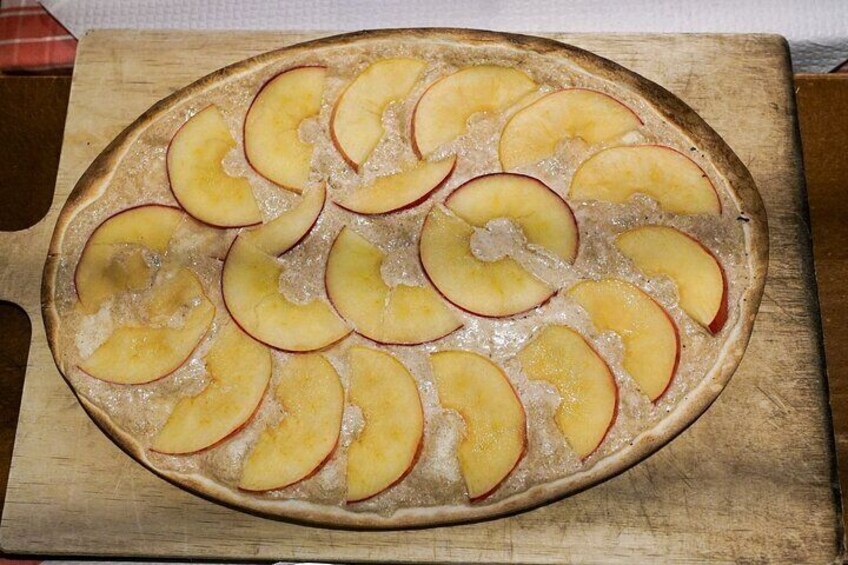 A pizza with apple slices on a wooden board. 2
