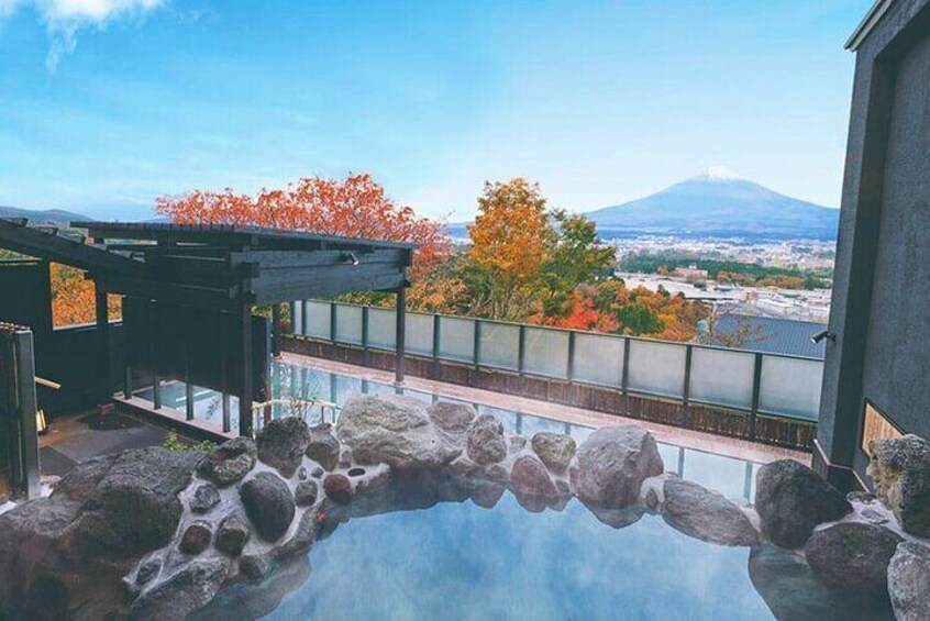 A stone bridge over a reflective water surface, with autumn foliage and a mountain in the background. 1