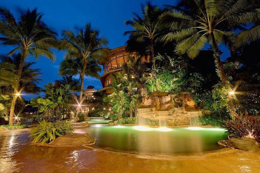 Ein Resort mit Pool, Palmen und einem Gebäude mit Wasserfall. 4