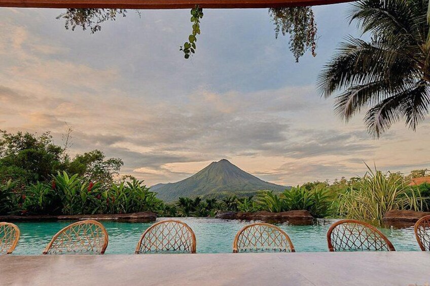 Une piscine entourée de chaises, une montagne en arrière-plan et une végétation tropicale. 2