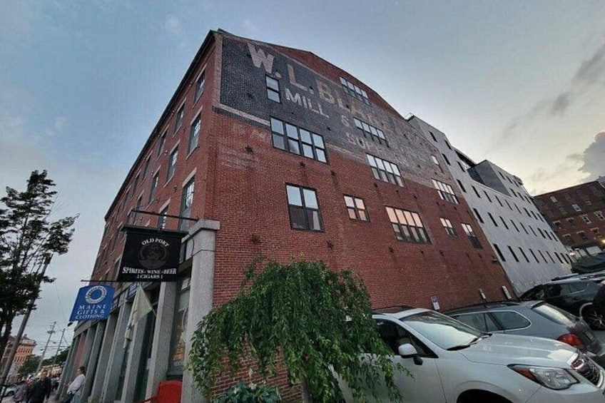 A multi-story brick building with signage for 'W.L. Smith' and 'Old Port' on the ground floor. 2