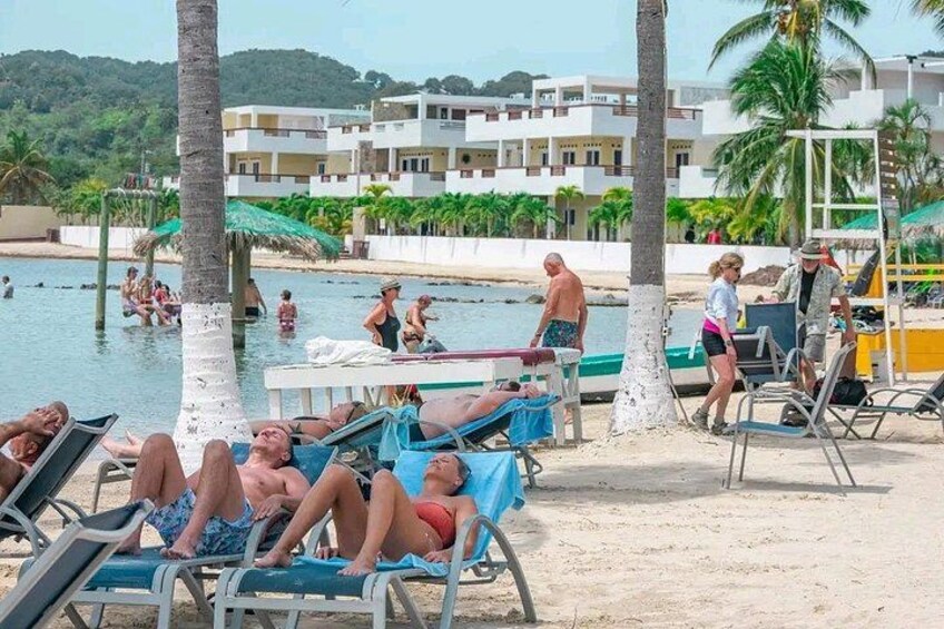 Una spiaggia con persone che prendono il sole, nuotano e passeggiano. 5