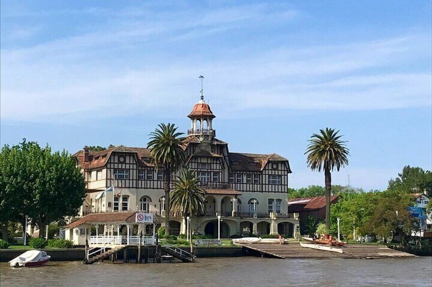 Un edificio histórico con una torre destacada, un muelle y palmeras. 1