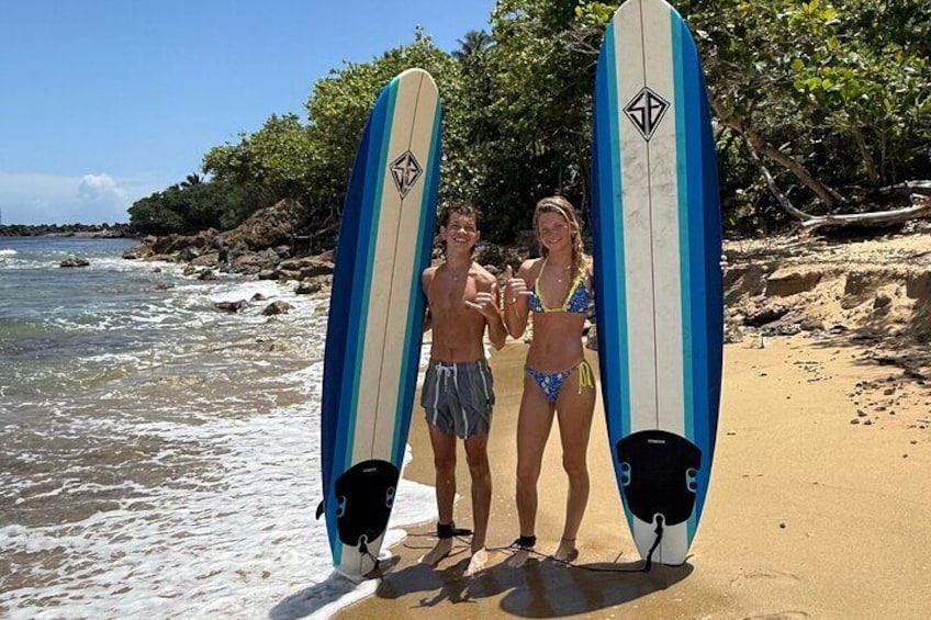 Two people holding surfboards on a sandy beach with ocean waves. 3