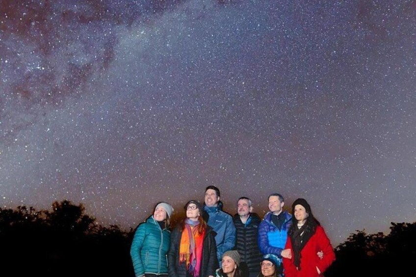 A group of people standing under a starry night sky. 3