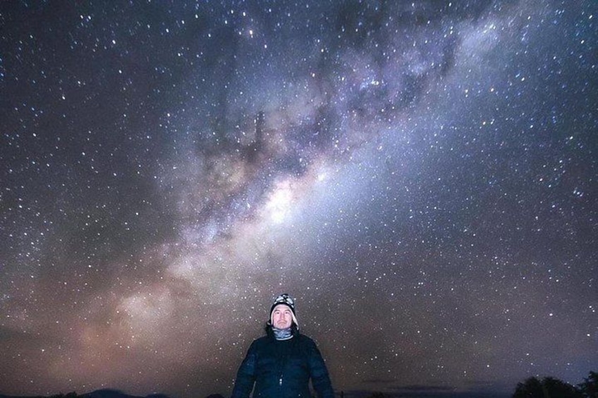 A person standing under a starry night sky with a visible Milky Way. 5