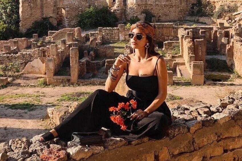 A person sitting on a stone wall in an ancient ruin with columns and stone structures in the background. 3