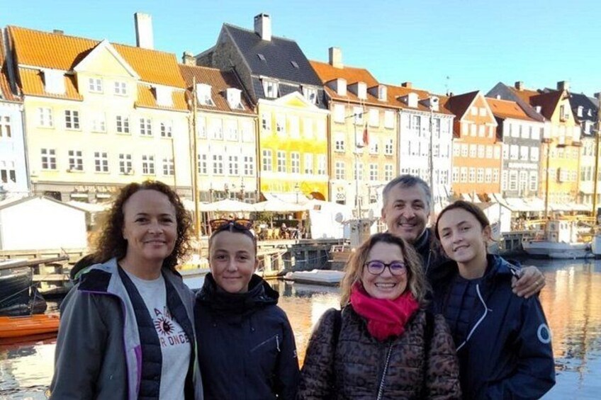 En gruppe mennesker står foran farverige bygninger ved vandet. 3