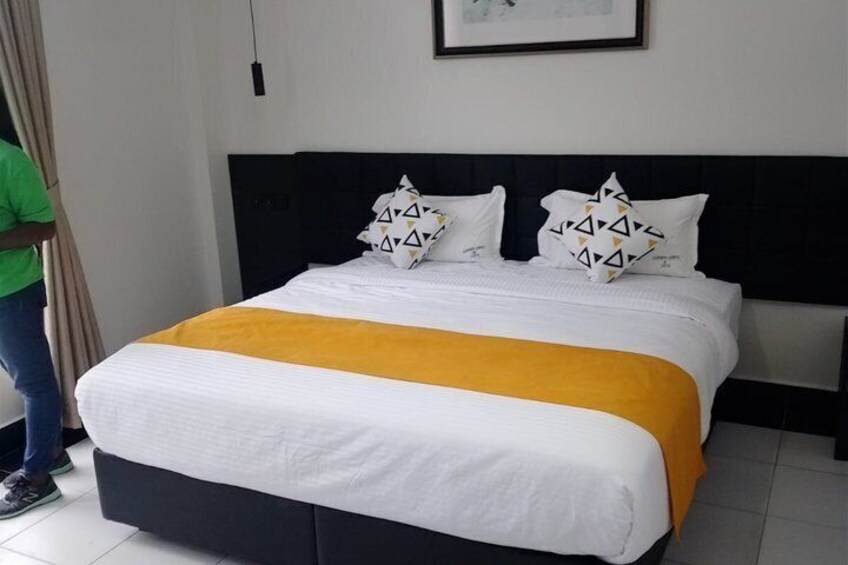 A neatly made bed with white and yellow bedding, a black headboard, and patterned pillows. 2