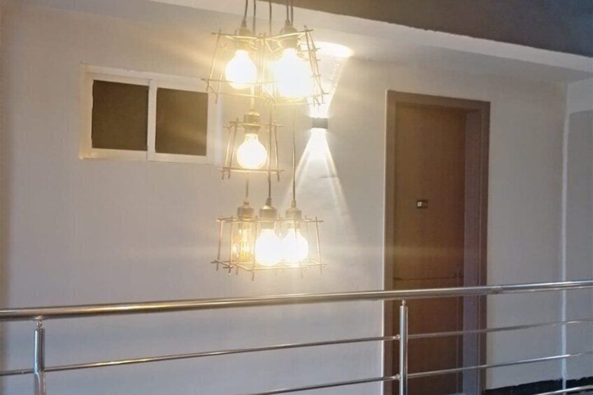 A staircase with a metal railing, a wooden door, and a wall-mounted light fixture with exposed bulbs. 3