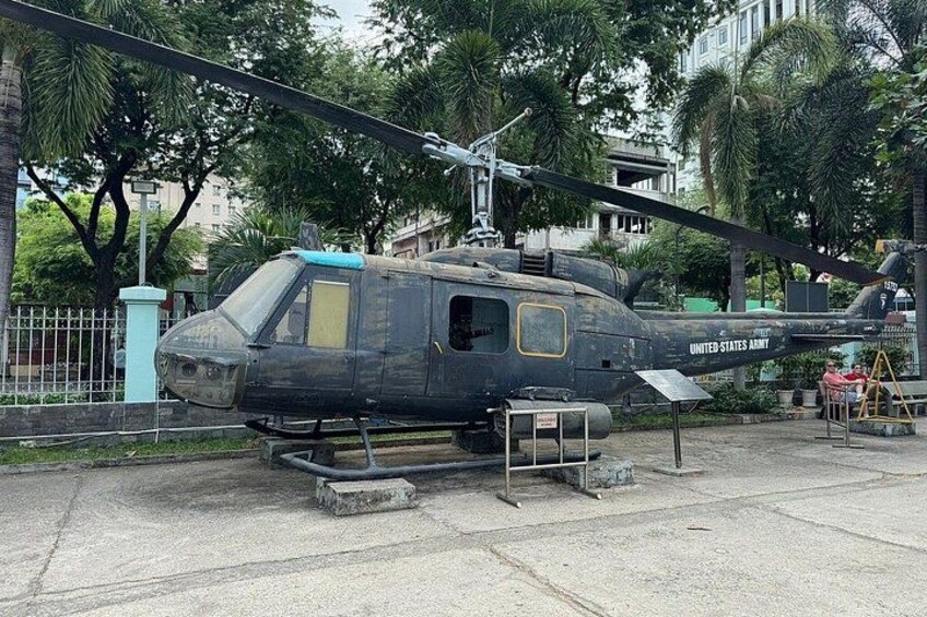 Un helicóptero del Ejército de los Estados Unidos estacionado sobre una superficie de hormigón, con árboles y edificios al fondo. 4