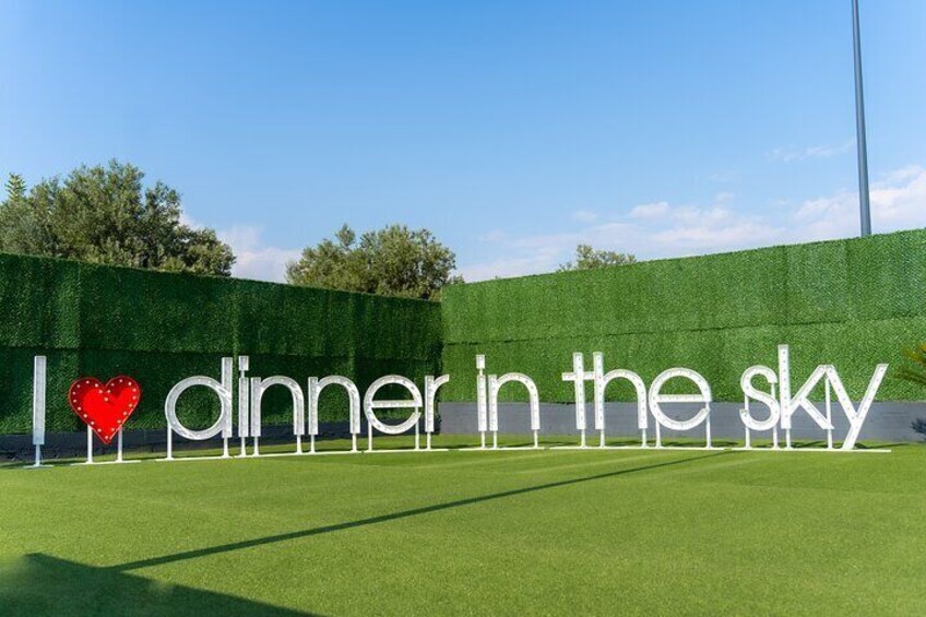 A sign with the text "I ♥ dinner in the sky" against a green backdrop. 1