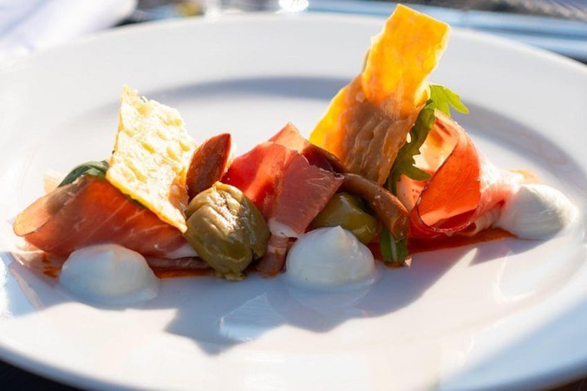 A white plate with a dish of food including smoked salmon, capers, and a green vegetable, possibly a pepper. 5