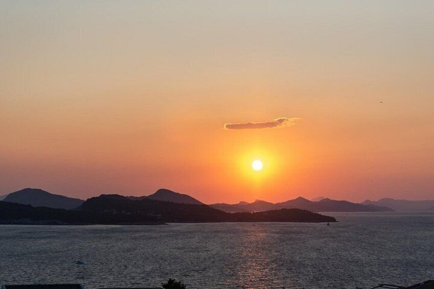 A sunset over a calm sea with distant mountains. 5