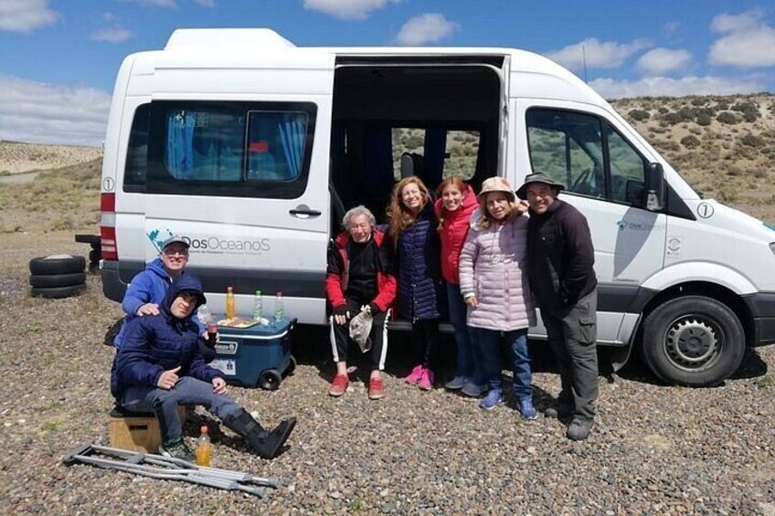 A group of people around a van with a cooler and camping gear. 2