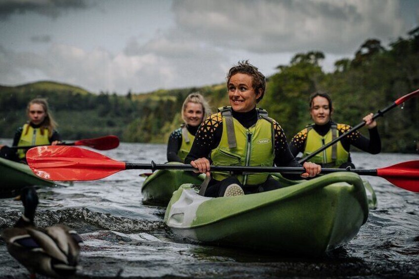 Three people kayaking on a river surrounded by greenery. 3