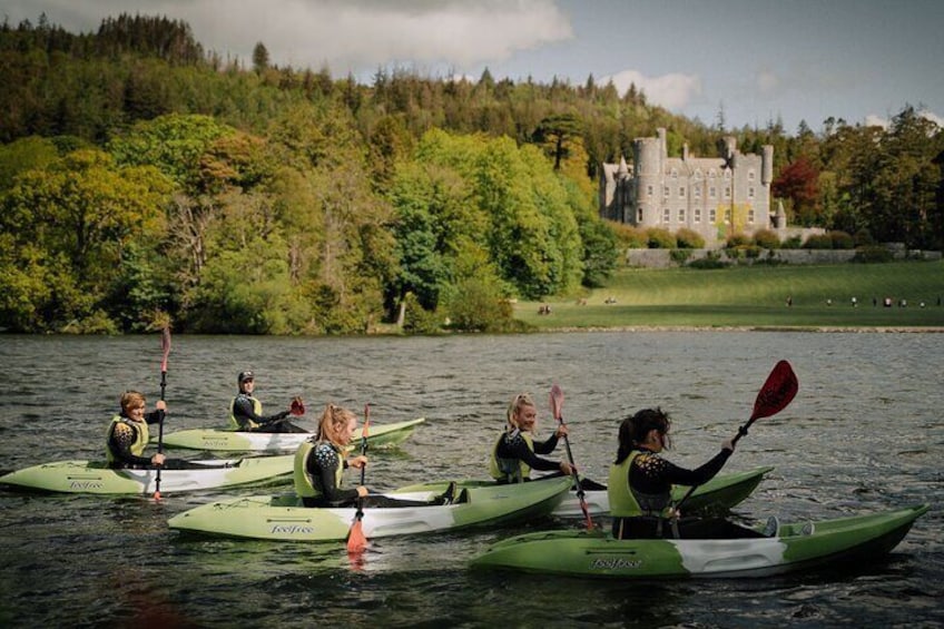 People kayaking on a lake with a castle in the background. 1