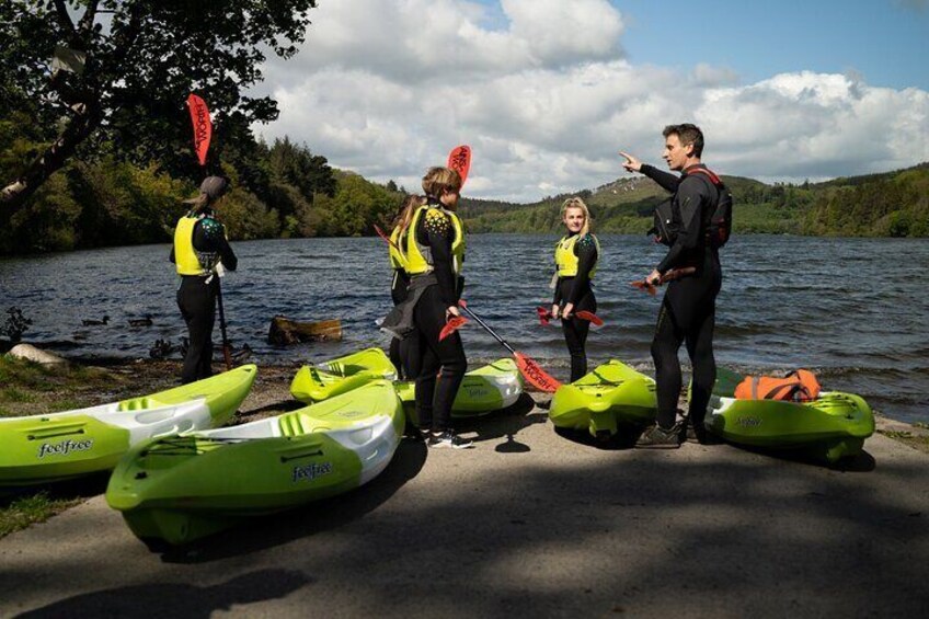 People standing by kayaks on a lakeside path. 5