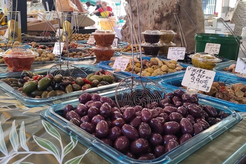 Un mercado con diversas aceitunas y verduras encurtidas expuestas en bandejas. 2