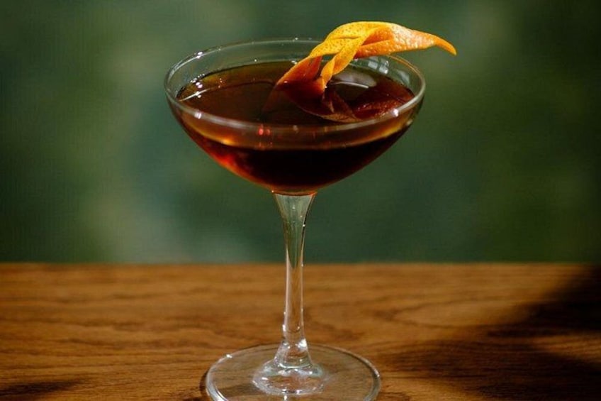 Un cocktail servi dans un verre à martini, agrémenté d’une garniture, sur une surface en bois. 2