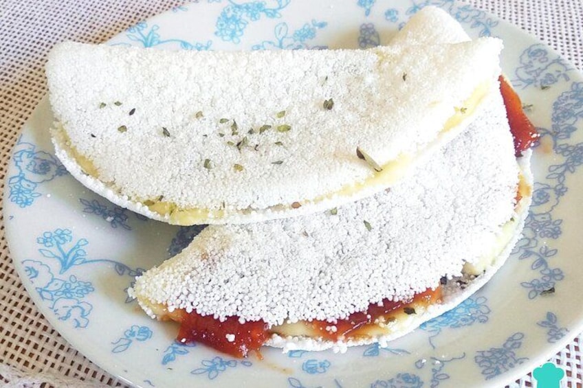 Un piatto con un cibo ricoperto di polvere bianca, probabilmente formaggio o una guarnizione, e salsa rossa sotto. 2