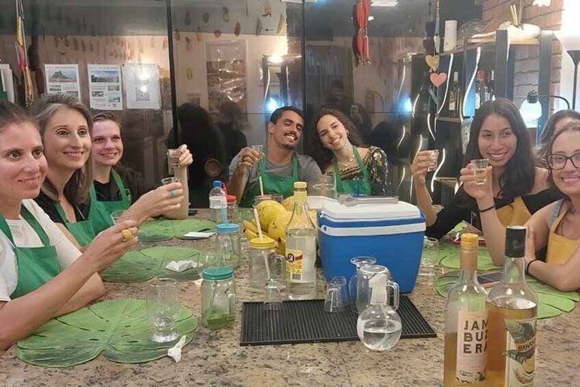 A group of people in aprons around a table with cooking ingredients and utensils. 3