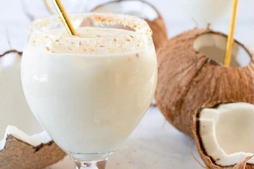 Un verre de lait de coco avec une paille, entouré de noix de coco. 4