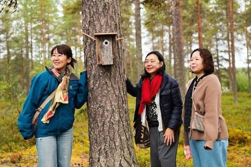 Three people standing by a tree with a birdhouse. 1