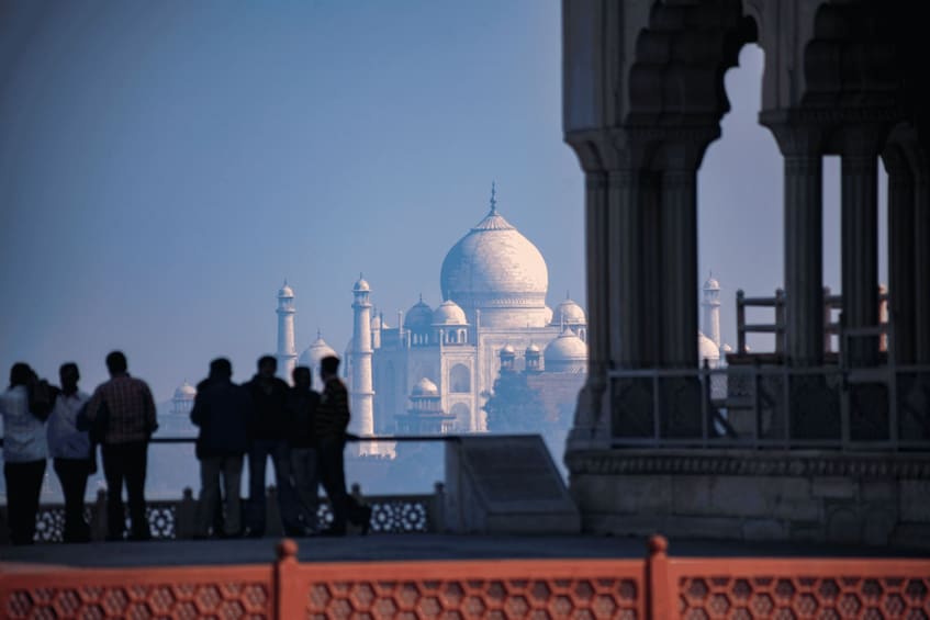 A group of people standing on a bridge with a view of the Taj Mahal in the background. 5