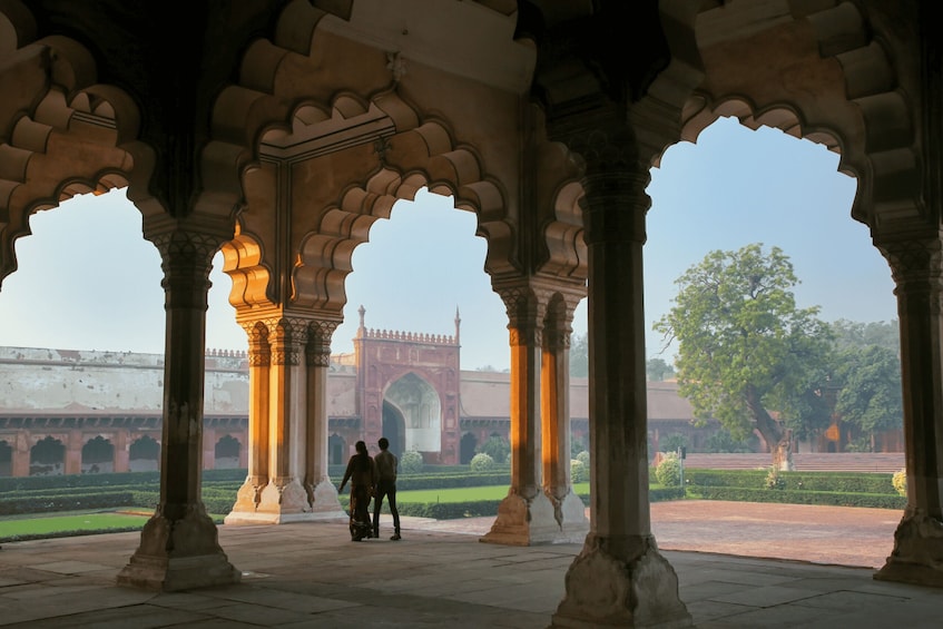 An architectural structure with arches and columns, a distant view of a large gate, and a well-maintained garden. 3