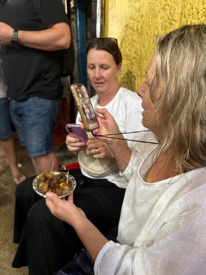 Una persona sosteniendo un teléfono inteligente y un plato de comida. 3