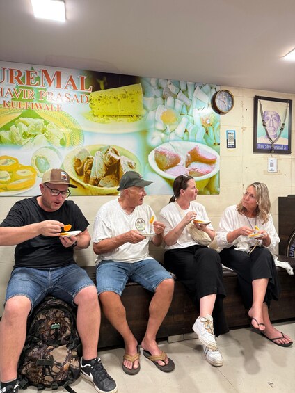 Cuatro personas sentadas en un banco, comiendo. 2