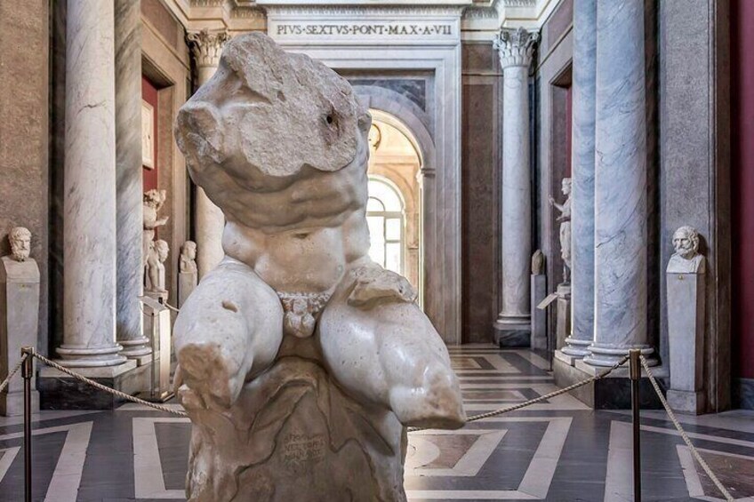 A marble statue of a muscular figure in a classical architectural setting with columns and a patterned floor. 4