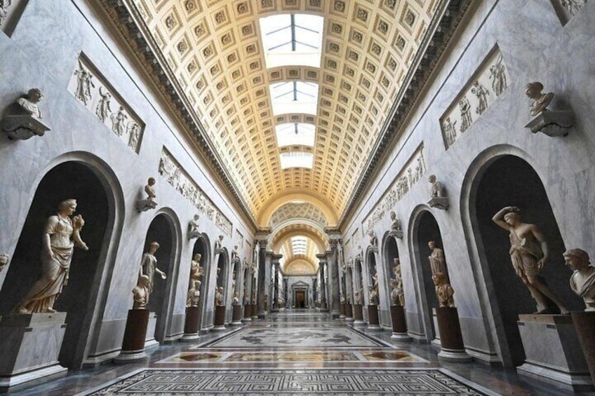 A grand hallway with statues lining the walls, a high ceiling with a skylight, and a patterned floor. 3