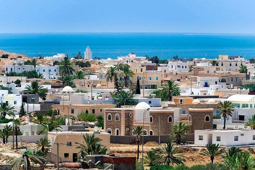 Un pueblo costero con edificios, palmeras y un mar azul cristalino. 4
