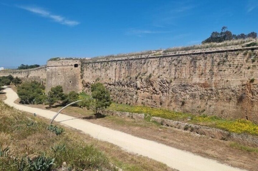 A stone wall with a pathway alongside it. 1