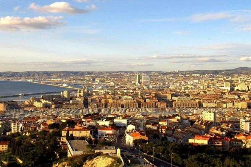 A coastal cityscape with a prominent waterfront, dense urban buildings, and a clear sky. 1