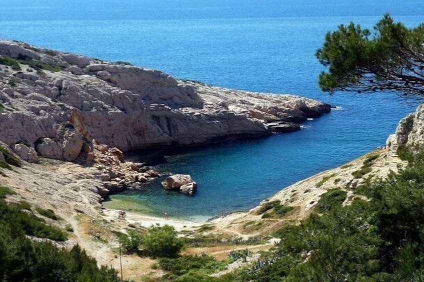 A coastal landscape with rocky terrain, clear blue sea, and sparse vegetation. 5