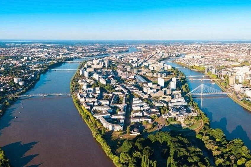 An aerial view of a city with a river, a bridge, and a dense cluster of buildings. 2
