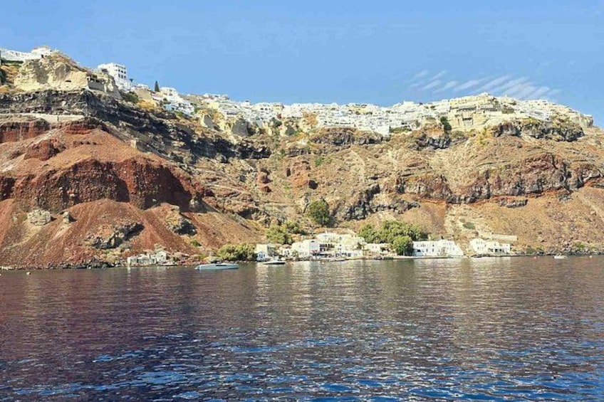 A coastal town with buildings on a hillside, a body of water in the foreground, and a clear sky. 3