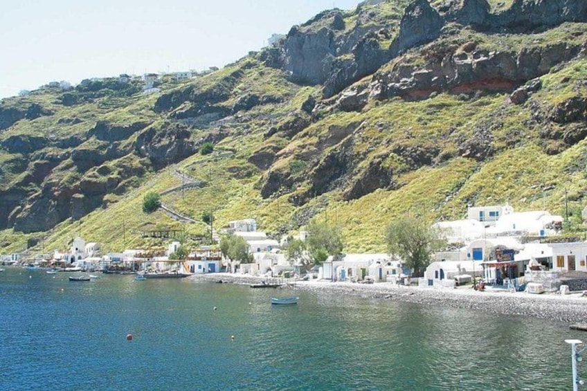 A coastal village with white buildings, boats, and a rocky hillside. 4