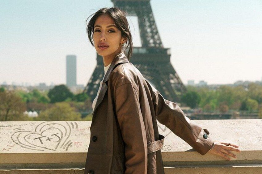 A person standing with arms outstretched in front of the Eiffel Tower. 2