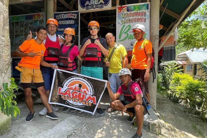 A group of people in a tropical setting with a sign that reads 'LAGU ADVENTURE.' 4